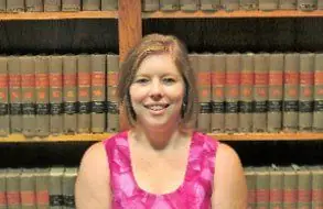 Melinda J. Rodgers, legal assistant, in front of shelves of law books